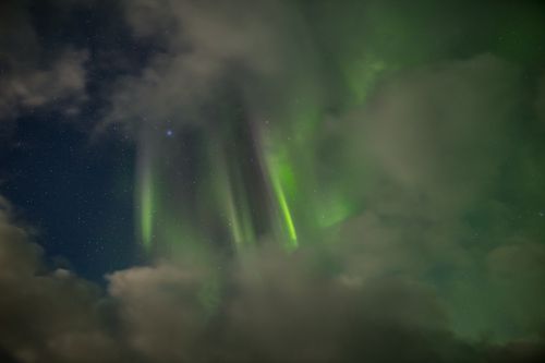 Auroral curtains surrounded by clouds